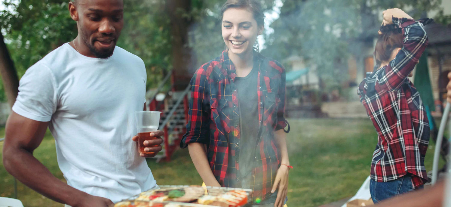 Smoky barbecue gathering with friends grilling meats and veggies outdoors, showcasing joy in outdoor cooking.
