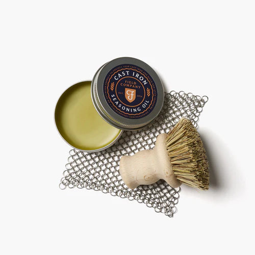 Field Company Cast Iron Care Kit featuring seasoning oil, chain mail scrubber, and natural fiber brush for grilling.
