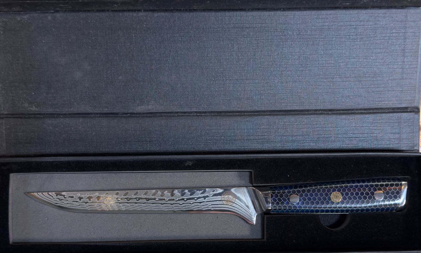 Spaceman Interstellar Boning Knife-Blue displayed in a sleek black box showcasing its Damascus steel blade.