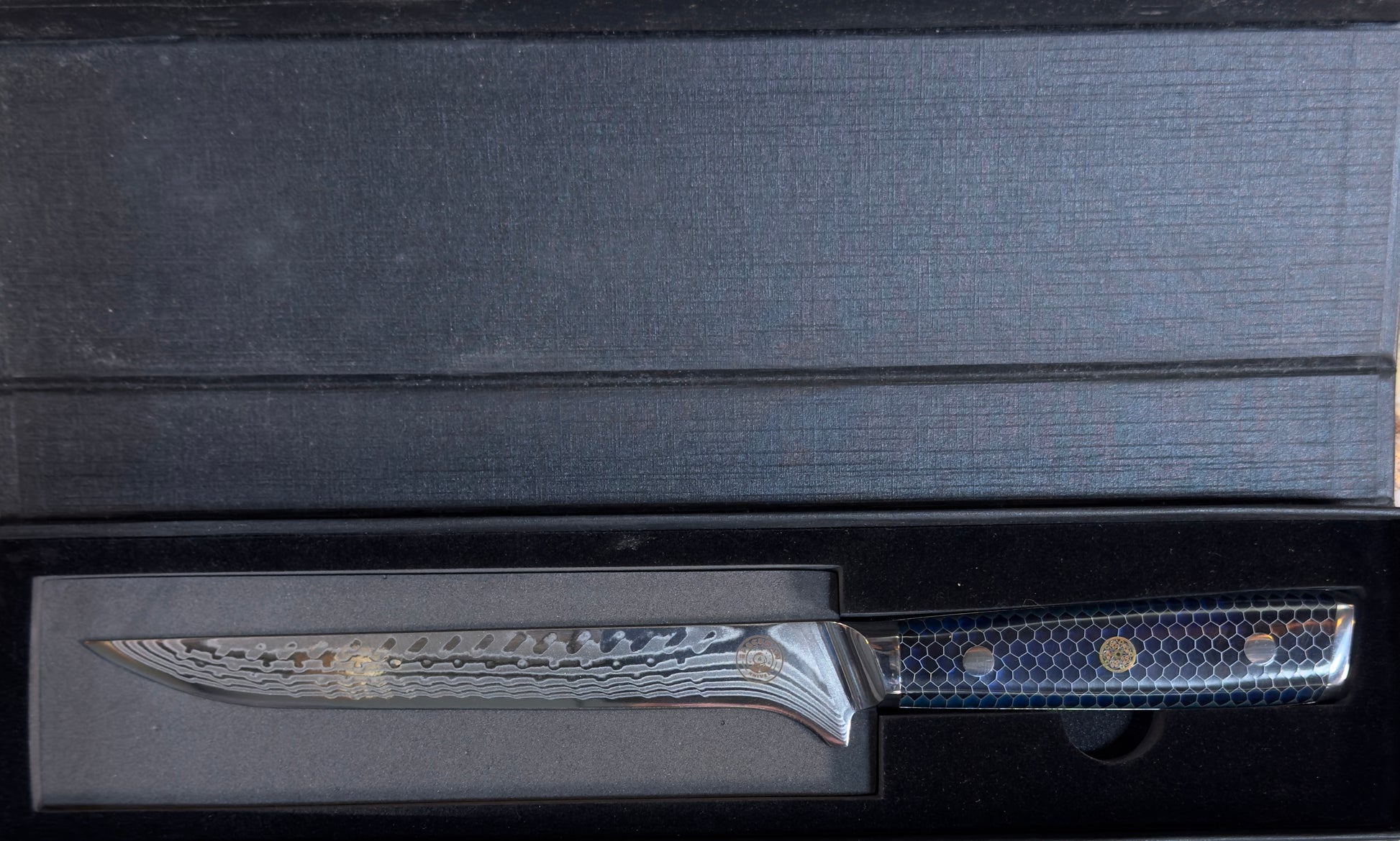 Spaceman Interstellar Boning Knife-Blue displayed in a sleek black box showcasing its Damascus steel blade.