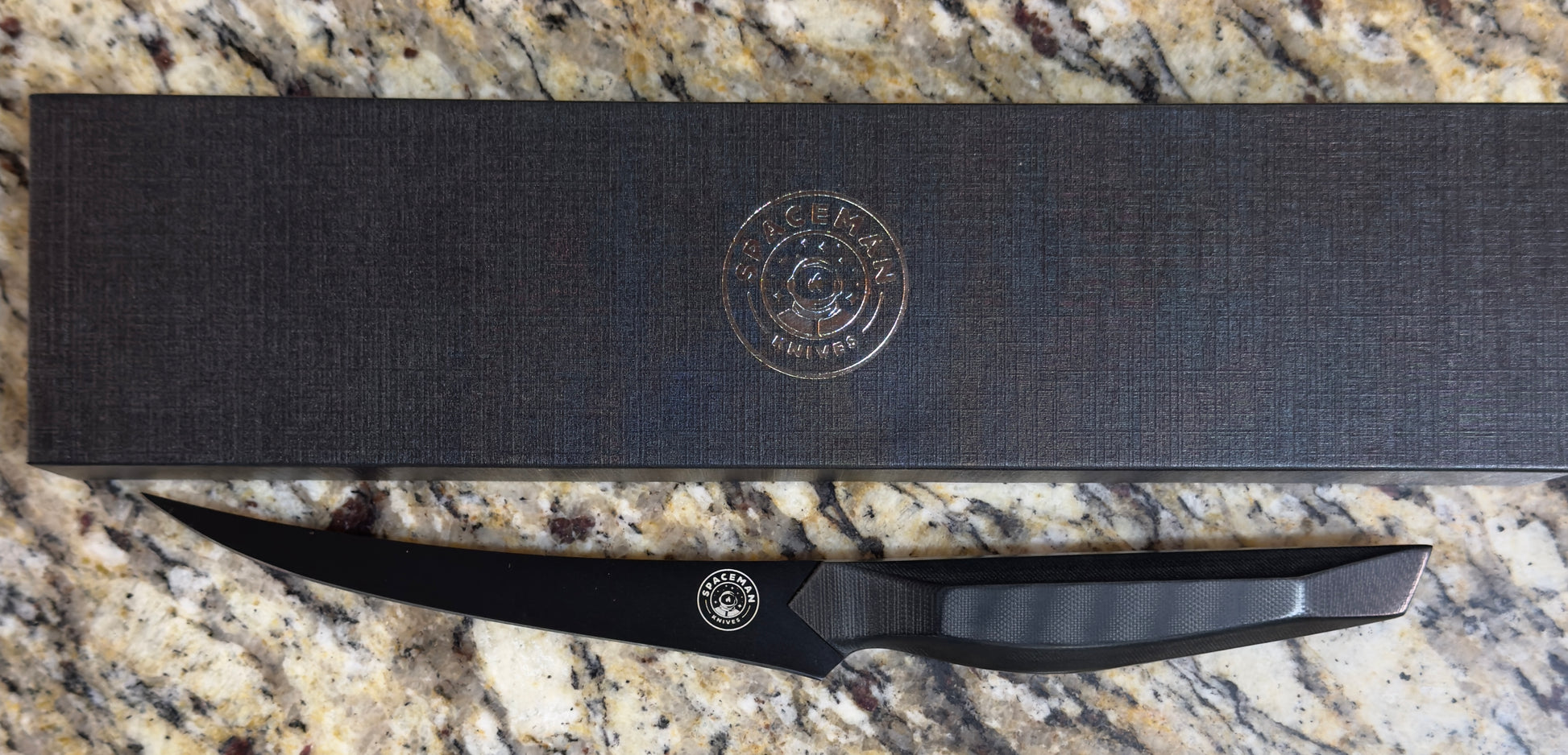 Spaceman Dark Matter Boning Knife displayed on a granite countertop with a sleek packaging.
