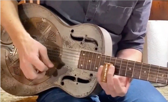 Person playing a resonator guitar, showcasing fingerpicking technique and traditional music style.