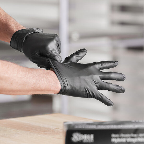 Person putting on Hybrid Vinyl/ Black Disposable Nitrile Gloves for barbecue preparation and cooking.