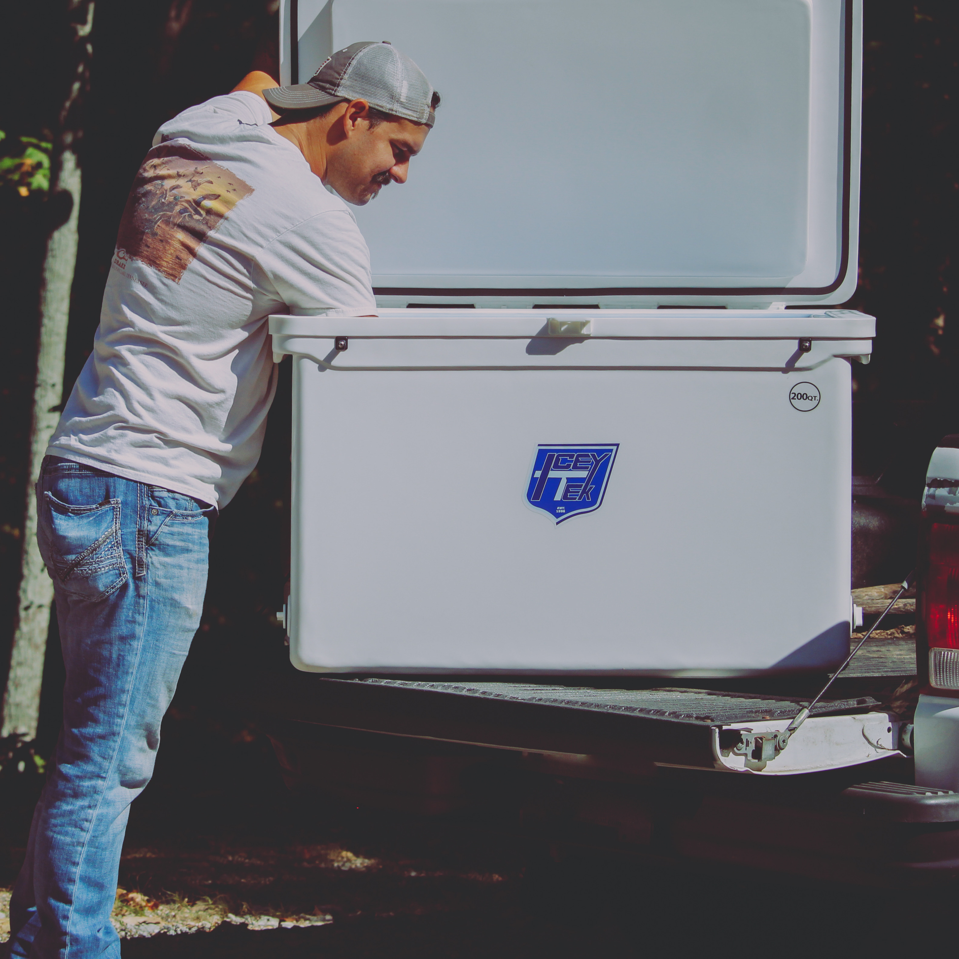 Person loading the ICEY-TEK 200 Quart Cooler (FREE SHIPPING) into a truck for outdoor adventures.