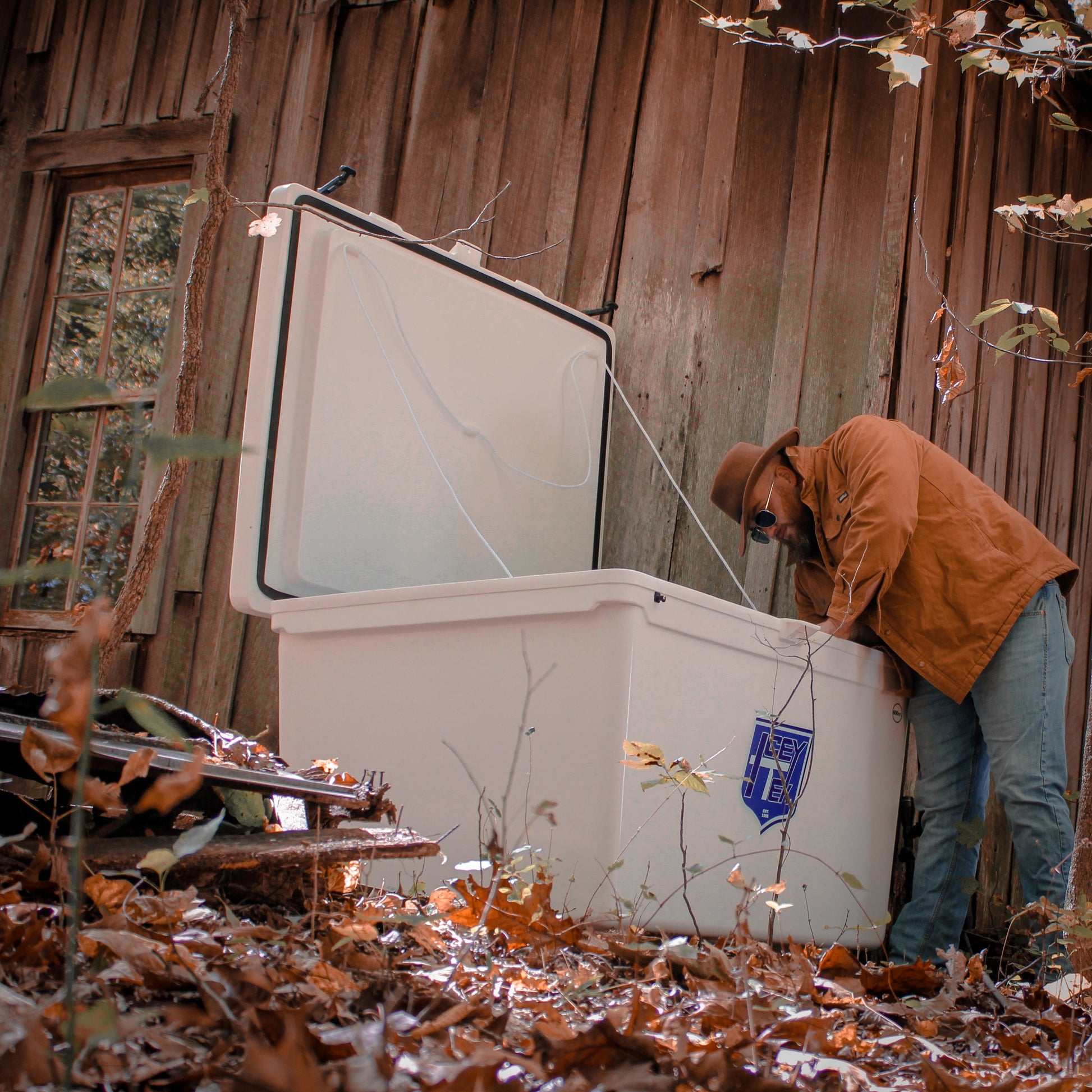 Person inspecting an ICEY-TEK 600 Quart Cooler (FREE SHIPPING) outdoors, ideal for grills smokers and cookers.