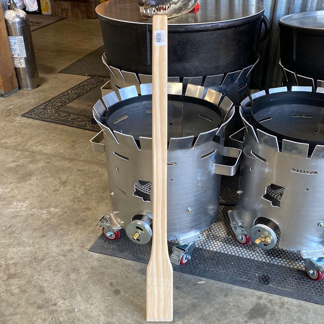Cajun Classic Wooden Mixing Paddle next to outdoor grills and cookers, perfect for BBQ enthusiasts and grilling tools.