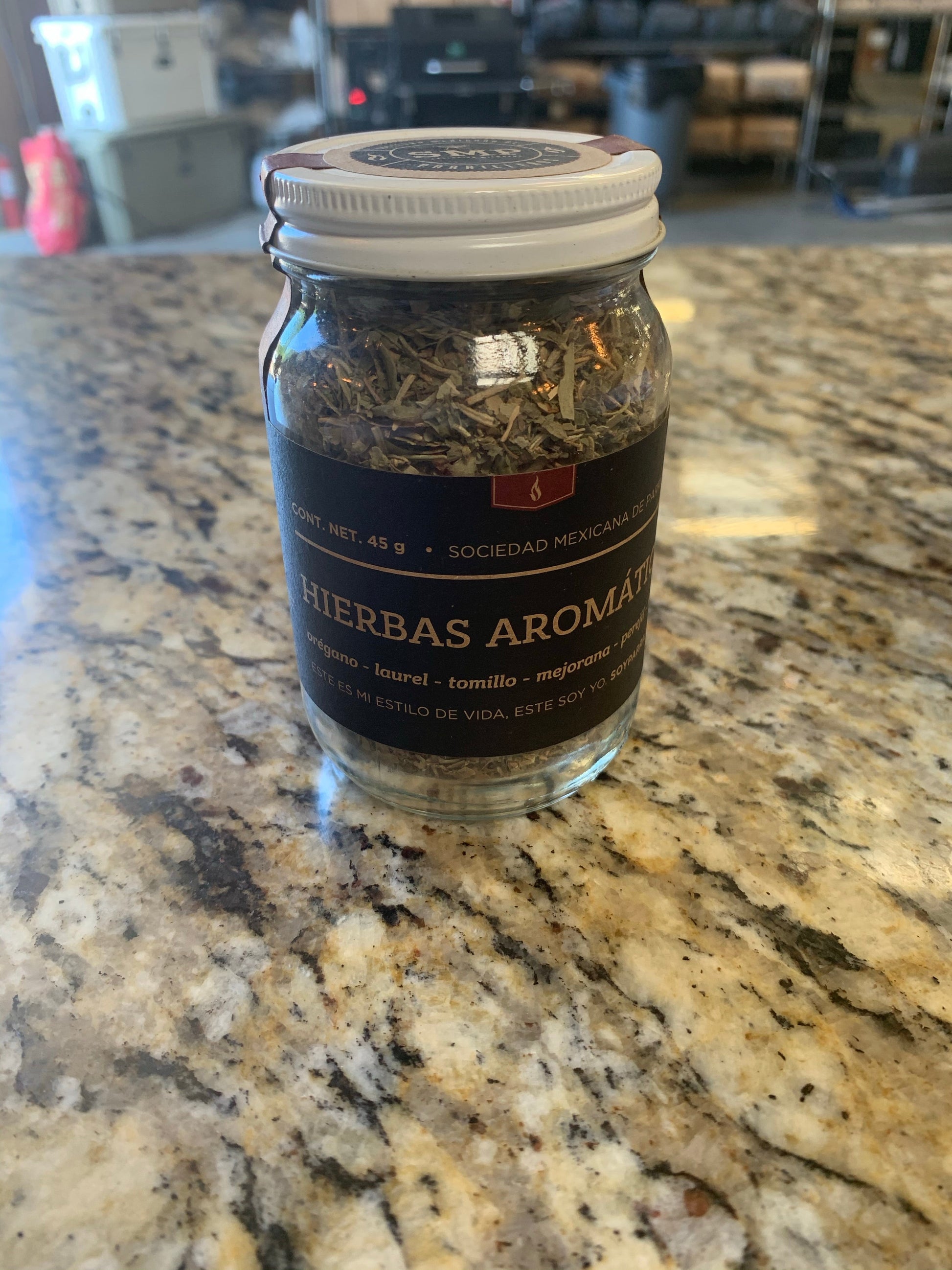 SMP rub jar with aromatic herbs on a granite countertop, perfect for grilling and barbecuing.