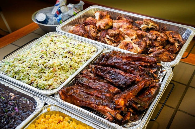 Catering Like a Pro: The Sweet Swine O' Mine Way to Event Success with BBQ ribs, chicken, and sides in trays.