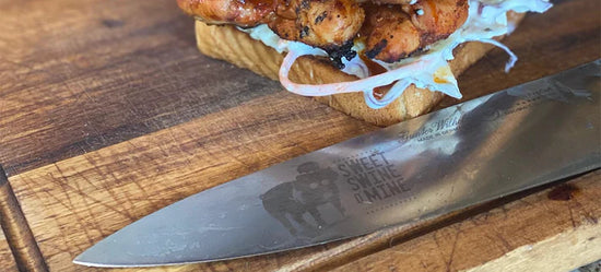 Grilled chicken sandwich on toasted bread with a professional BBQ knife on a wooden cutting board.