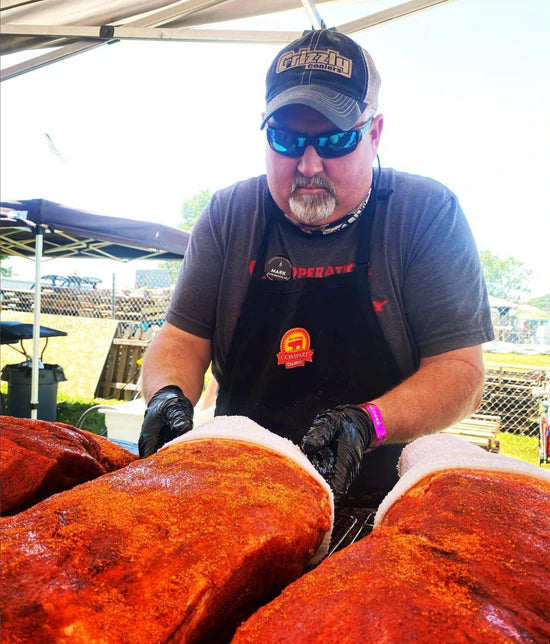 World-class pitmaster preparing BBQ ribs with spices at a competition using top smoker equipment.