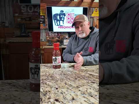 Sweet Sauce O' Mine Sweet & Spicy Vinegar 18 oz showcased by a barbecue enthusiast in a kitchen setting.