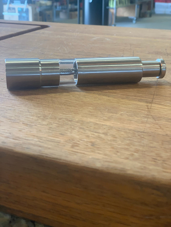 Spice Grinder with push button thumb design on wooden table, essential cooking tool for outdoor grills and smokers.
