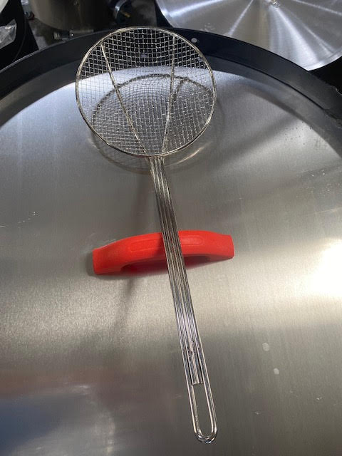 Cajun Cookware 6” Wire Skimmer on stainless steel surface for cooking and frying outdoor foods.